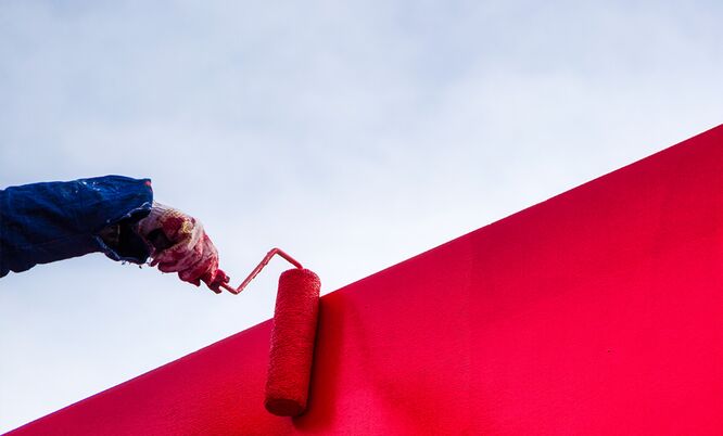 Malerarbeiten an einer roten Wand mit Farbroller