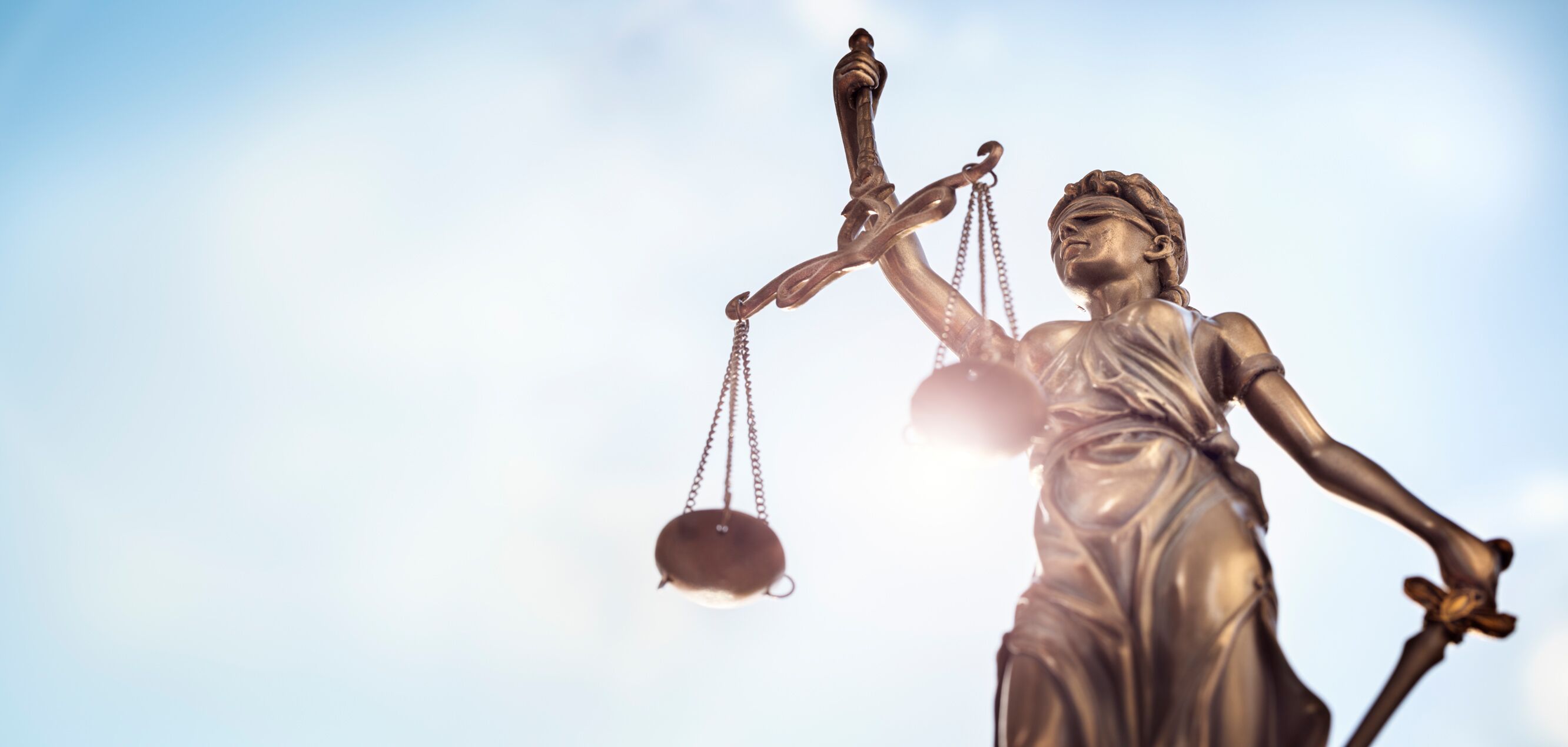 Justitia Staue vor blauem Himmel