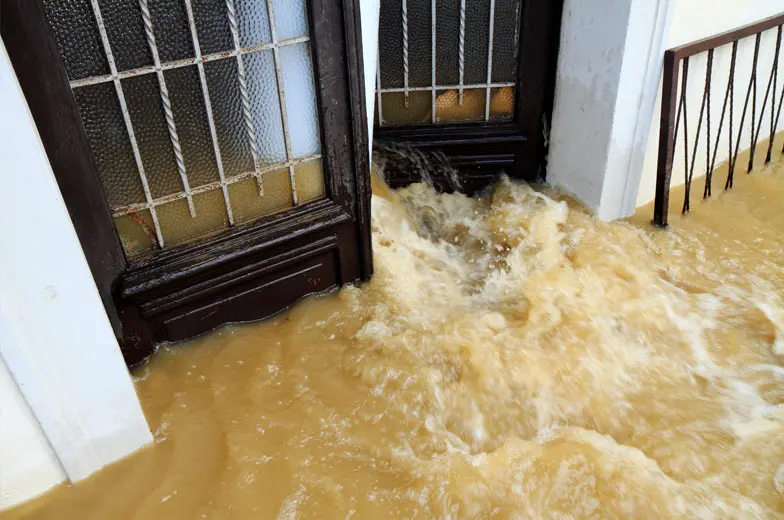 Eindringendes Hochwasser in einem Gebäude mit überflutetem Treppenbereich und stark strömendem, verschmutztem Wasser.