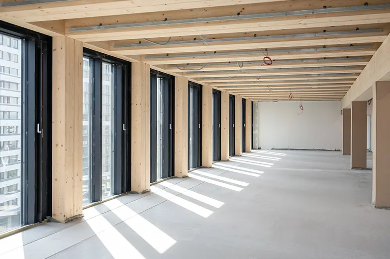 Moderner Innenraum im Holzbau mit großen Fensterflächen als Beispiel für nachhaltiges und gesundheitsbewusstes Bauen.
