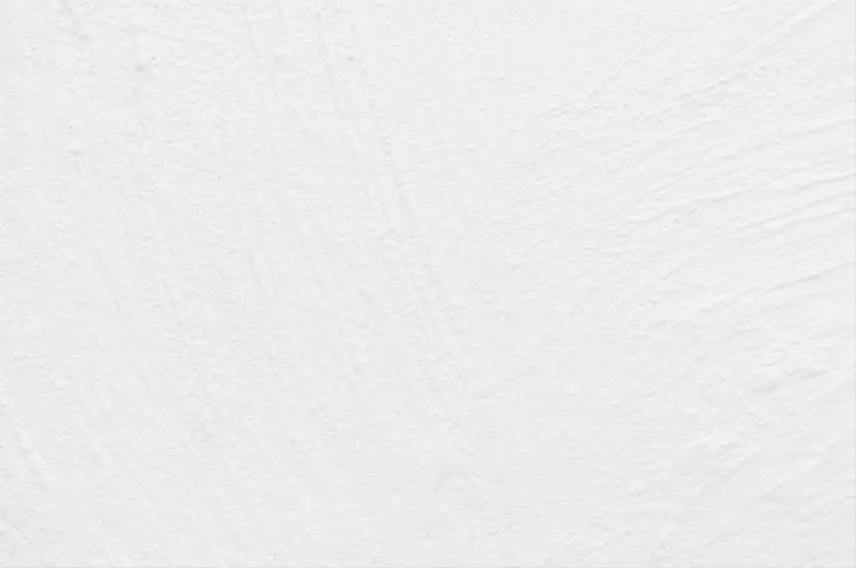 Eine weiße, leicht strukturierte Oberfläche mit subtilen, unregelmäßigen Mustern und Texturen, die leichte Schatten und Linien bilden, vermutlich Pinselstriche oder leichte Oberflächenunebenheiten.