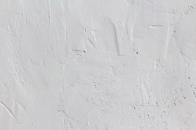 Maximal einheitliche hellgraue Fläche mit strukturierter, ungleichmäßiger Putztextur. Vereinzelt sind feine Risse und Einkerbungen zu erkennen.